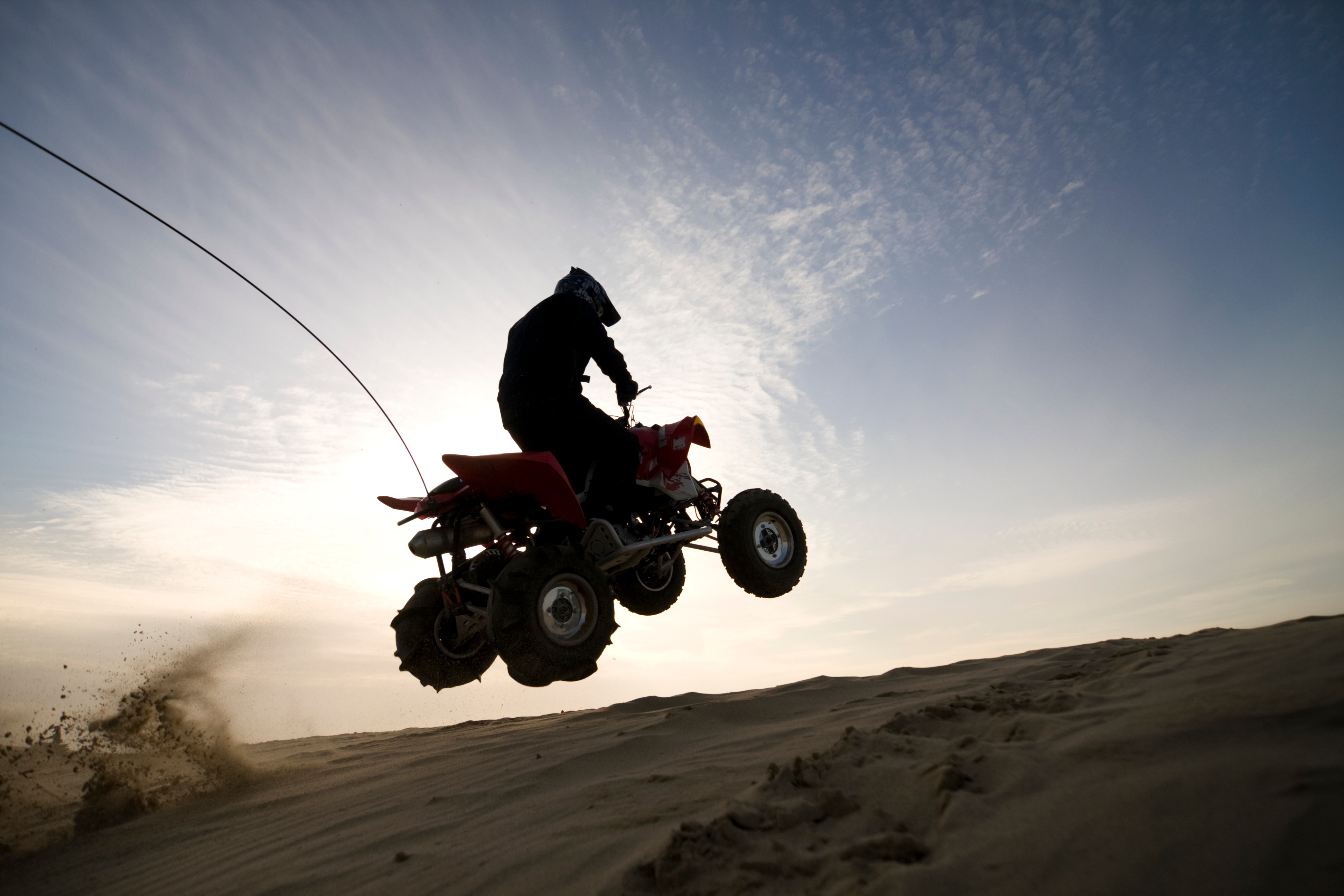 Silhouetted Person jumping an ATV